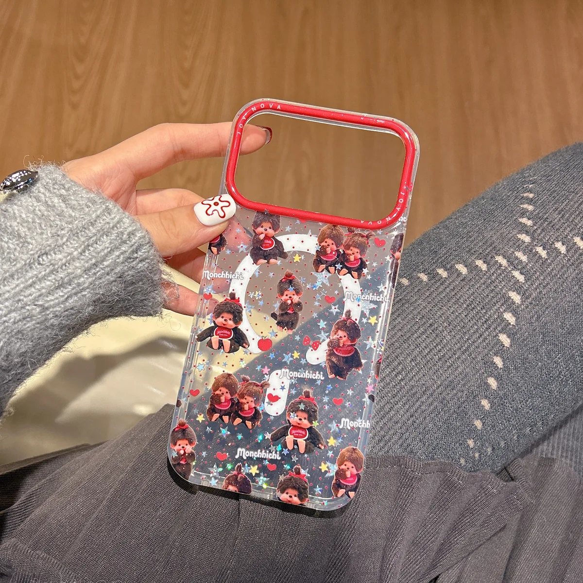 Clear glitter phone case with Monchhichi character print and red camera frame, held in hand